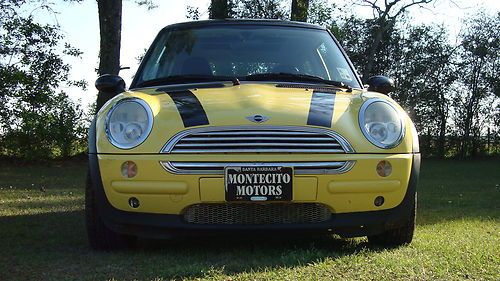 Yellow mini cooper with black racing stripes and sun roof.