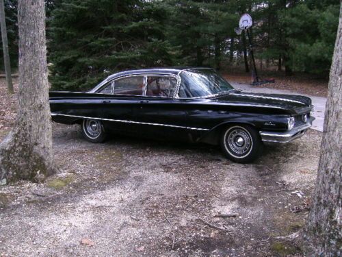 Two 1960s buicks, red two doors, black four doors