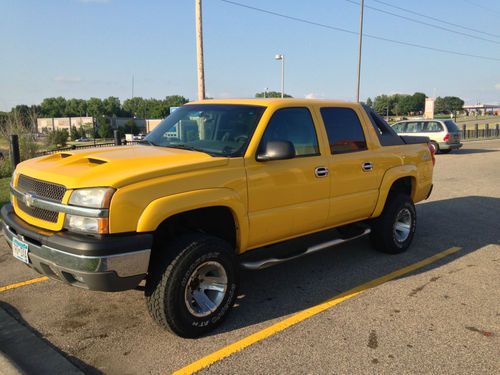 Yellow avalanche with a lift kit and over sized  tires and dual exhaust