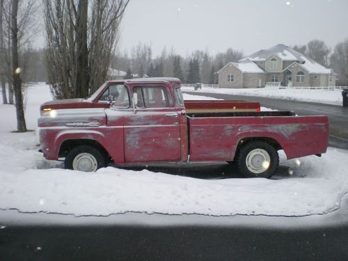 Red and white classic 1960 ford f-100 with wrap around back window.